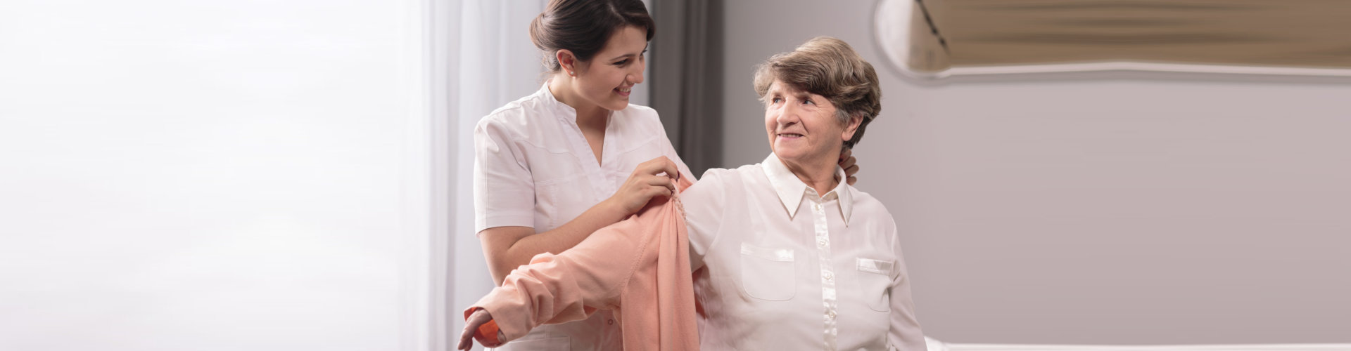 caregiver helping senior woman get dressed